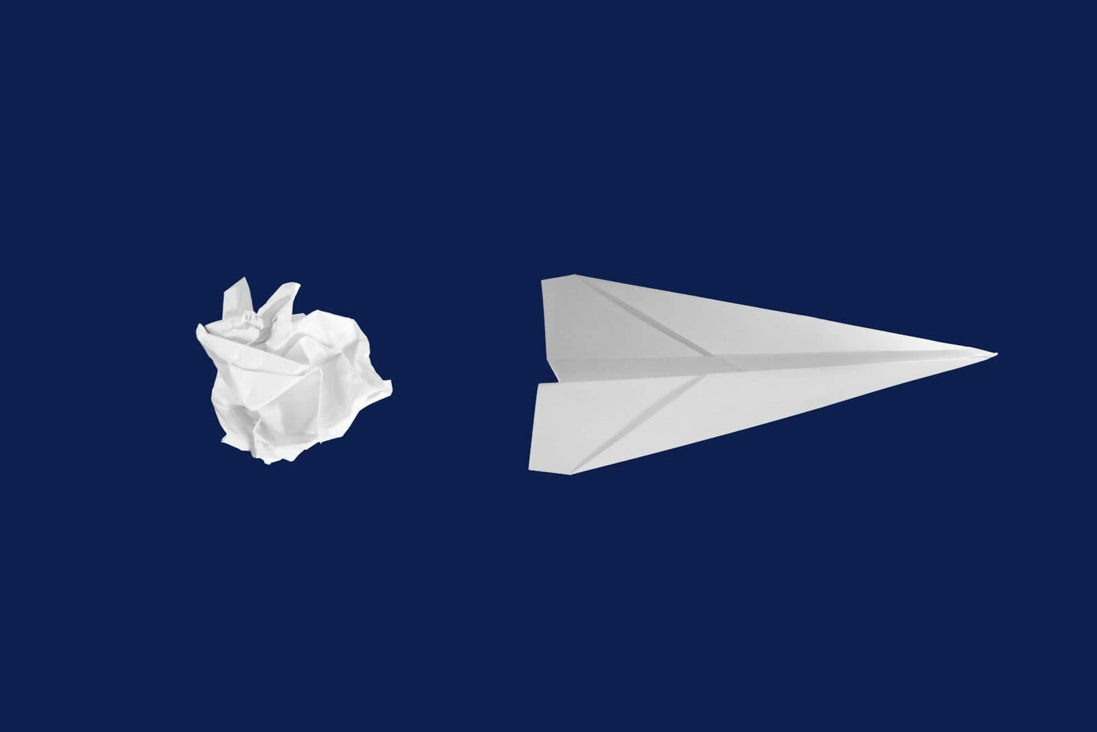 Sur un fond bleu nuit, une feuille froissée en boule à côté d’un avion en papier prêt à voler.